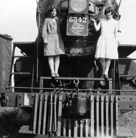 Clara May and friend on front of train, around 1923